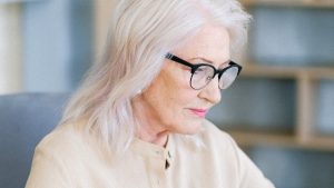 Aged woman in eyeglasses surfing internet on laptop | Breast Cancer Car Donations